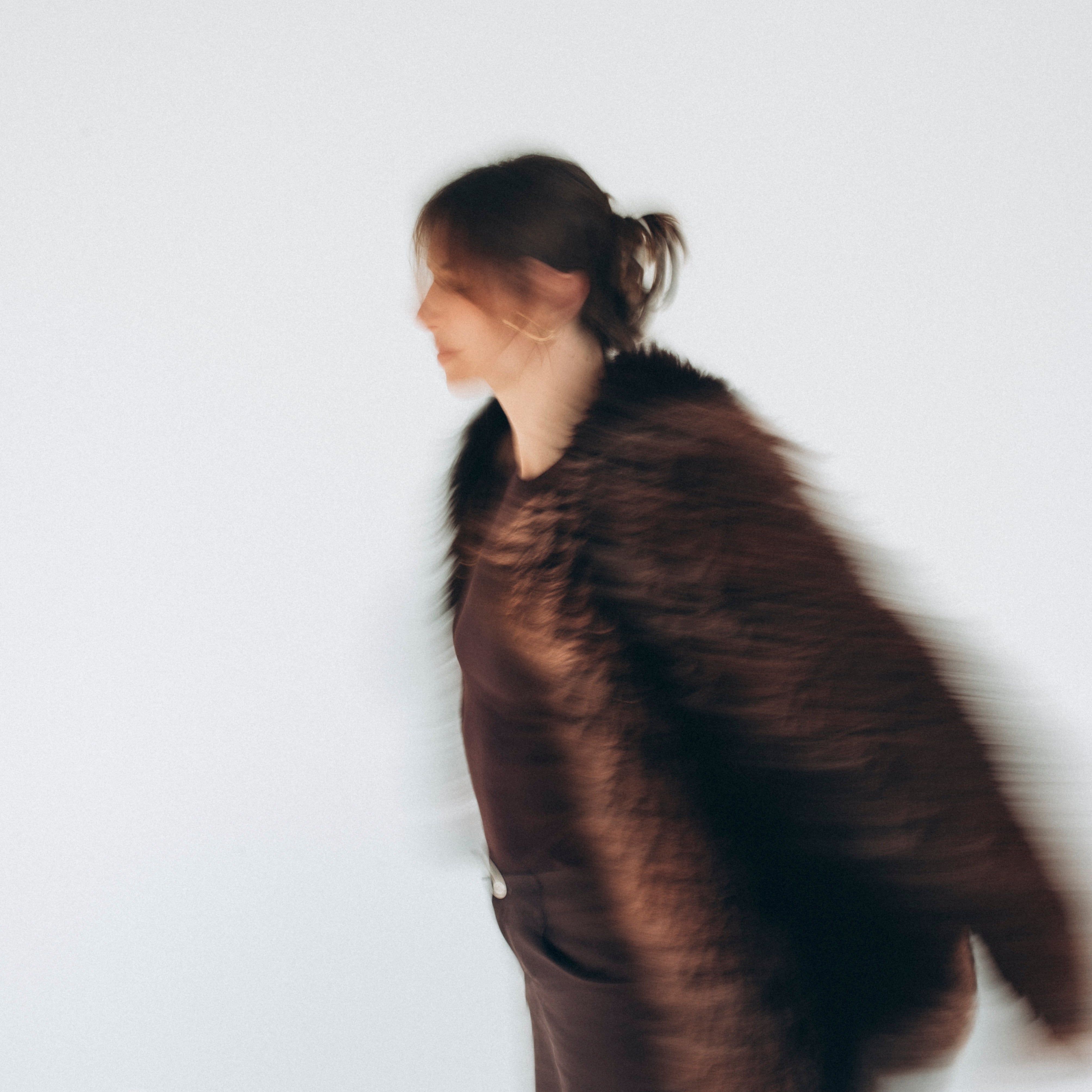 Woman in motion wearing ZUBEK’s chocolate brown sheepskin fur coat. Natural, non-toxic, and sculpted for clean, elevated outerwear.